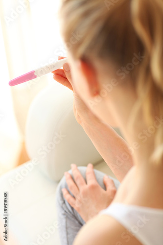 Smiling young woman looking on pregnancy test 