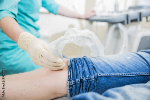 closeup hand of woman doctor doing an ultrasound looks at the leg and knee of the patient