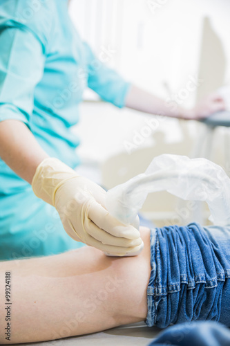 closeup hand of woman doctor doing an ultrasound looks at the leg and knee of the patient in the medical center