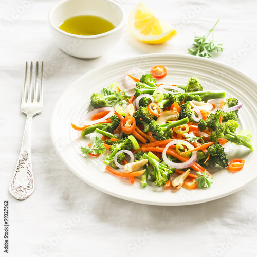 healthy salad with broccoli and carrots on a white plate on a light surface