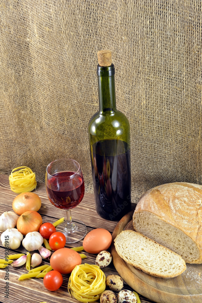 Naklejka premium Photo still-life of standing on the table a bottle of red wine and wine glass pasta with bread and vegetables for dinner