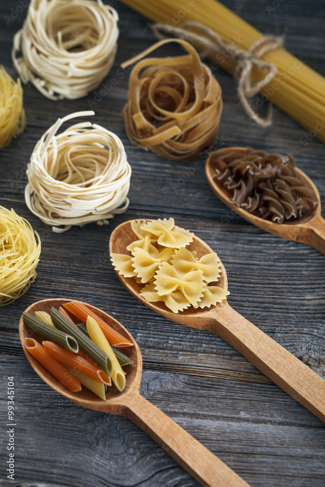 A set of raw pastas on spoons on a wooden table