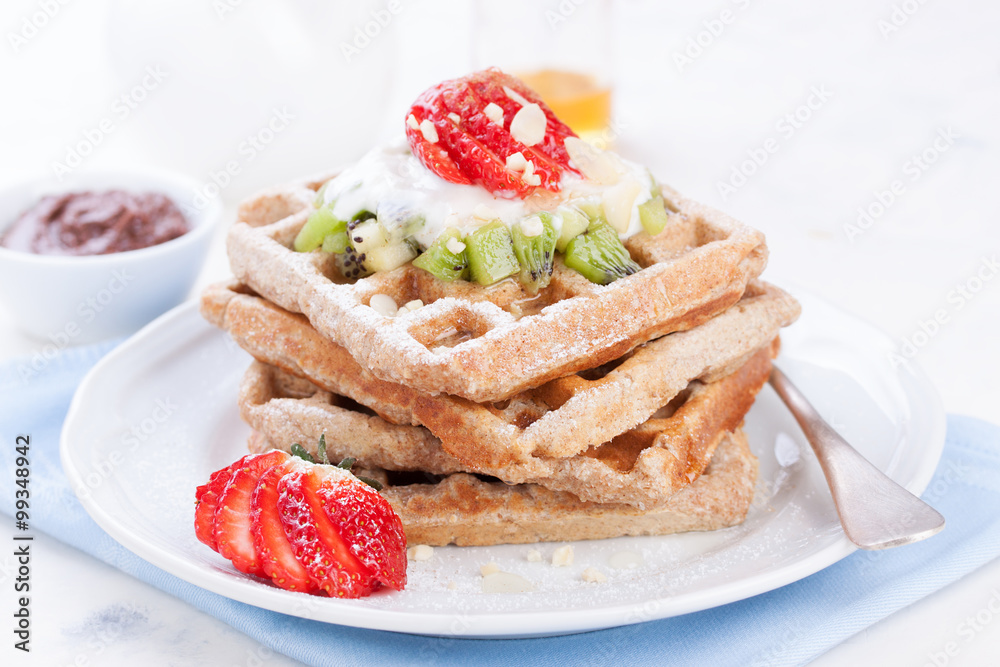 Waffles with wholewheat flour and fruits on a white plate on a blue napkin Waffles with wholewheat flour and fruits on a white plate on a blue napkin