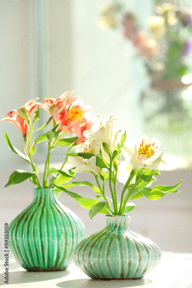 Beautiful Alstroemeria flowers in aquamarine vases on window background Beautiful Alstroemeria flowers in aquamarine vases on window background