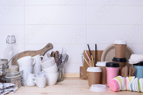 Various types of drink ware, ceramic and paper, on wooden lunch counter, white background.
