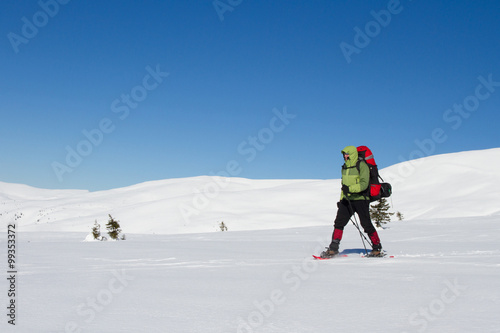 Winter hiking in the mountains on snowshoes with a backpack and tent.