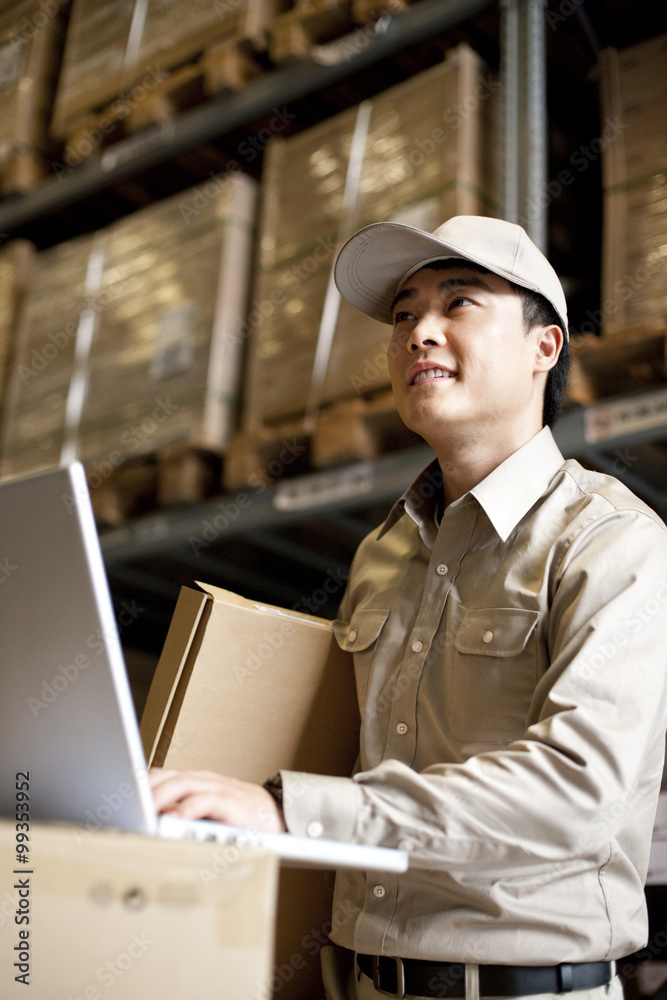 Worker using laptop in warehouse
