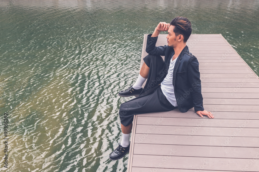 Handsome Asian model posing by an artificial basin Handsome Asian model posing by an artificial basin