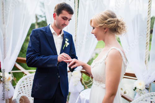 Fotografie Bride and groom exchange wedding rings and wear at the ceremony.