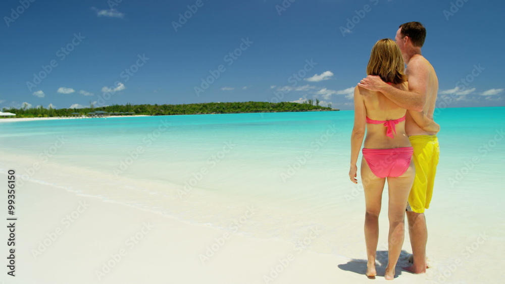 Barefoot Caucasian couple in swimwear holding hands on a tropical beach Barefoot Caucasian couple in swimwear holding hands on a tropical beach