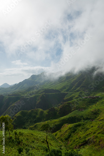 Misty fog over green mountain slope valley