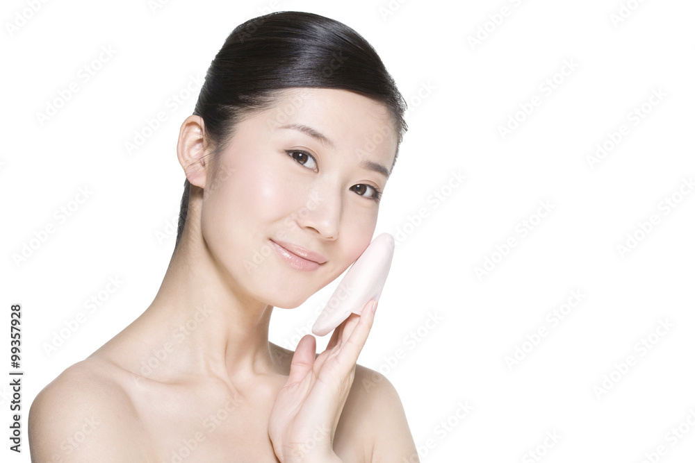 Beauty shot of a young woman holding a powder puff Beauty shot of a young woman holding a powder puff