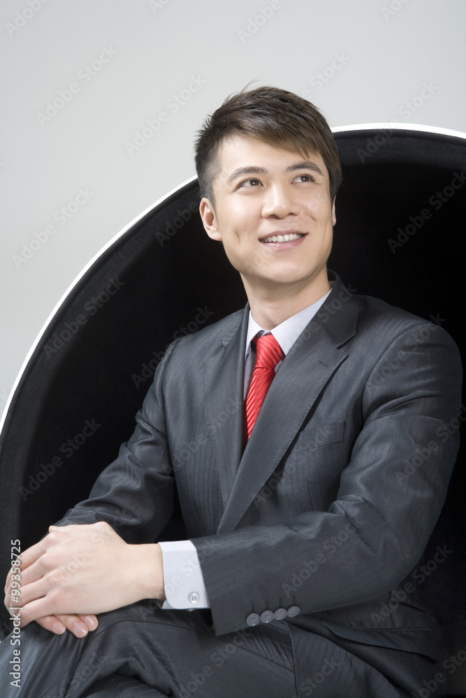 Confident young businessman sitting in a ball chair Confident young businessman sitting in a ball chair