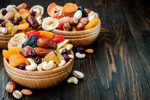 Photos Mix of dried fruits and nuts on dark wood background with copy space