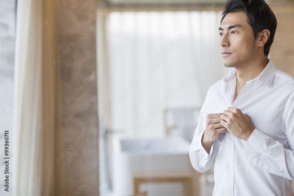 Young man buttoning shirt Young man buttoning shirt