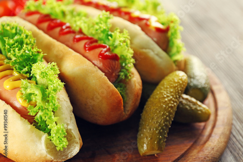 Tasty hot-dogs with vegetables on wooden table, close up