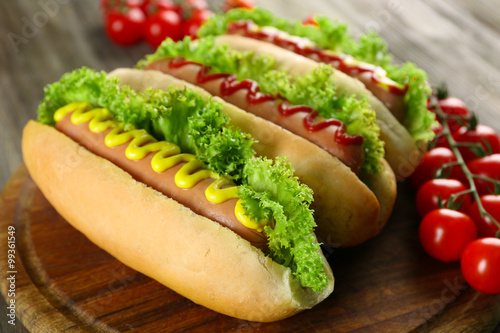Tasty hot-dogs with tomatoes on wooden background