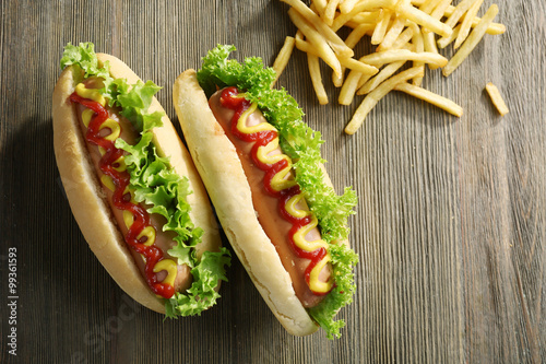 Tasty hot-dogs with French fries on wooden background