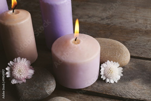 Spa set with candles  pebbles and flowers on wooden background  close up
