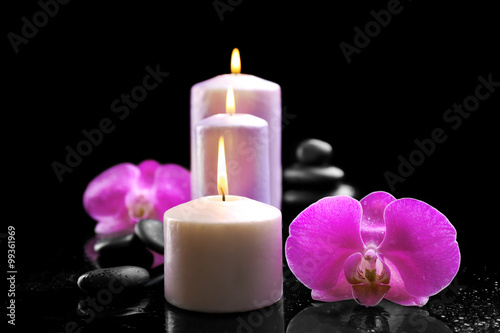 Composition of orchid, pebbles and candles in a row on dark background