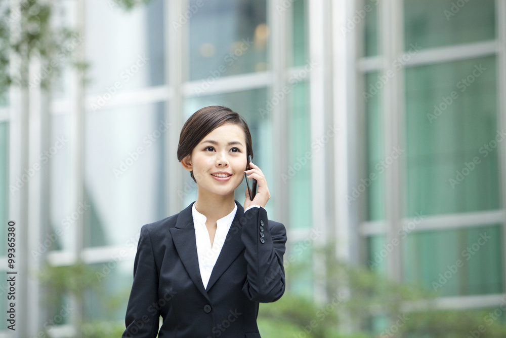 Young businesswoman on the phone outside a building, Hong Kong Young businesswoman on the phone outside a building, Hong Kong