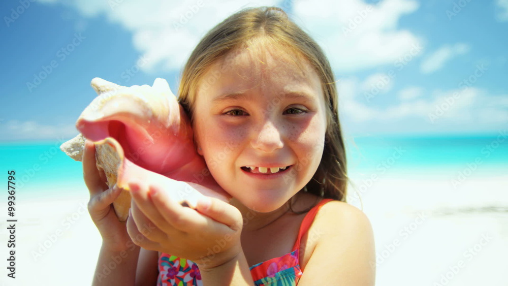 Portrait of cute young Caucasian girl on a beach vacation with a conch shell