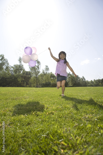 Young girl running with balloon outdoors