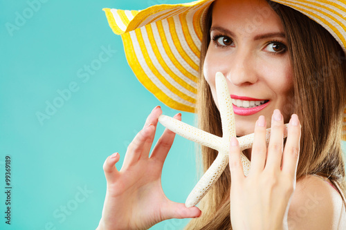 Woman in yellow hat holding white shell photo