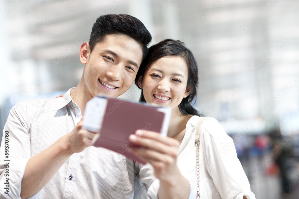 Young couple at the airport with flight tickets and passports Young couple at the airport with flight tickets and passports