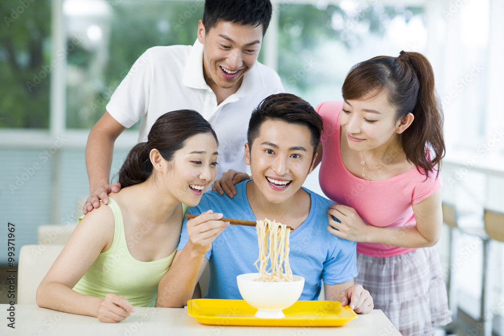 Young adults having noodles in restaurant Young adults having noodles in restaurant
