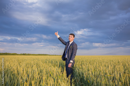 happy farmer, businessman, standing in wheat field with his hands and thumbs up © Ryzhkov Oleksandr