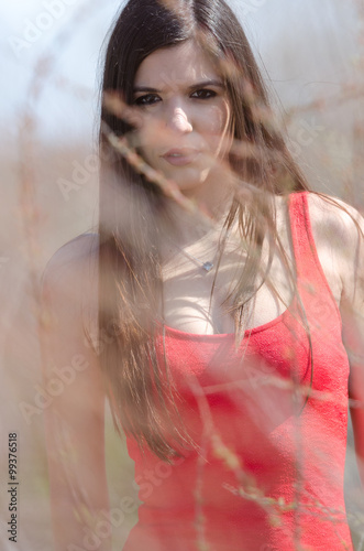 Lady standing behind dry grass looking at the camera