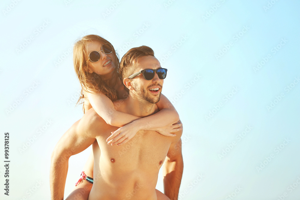 A guy carrying a girl on his back, at the beach, outdoors A guy carrying a girl on his back, at the beach, outdoors
