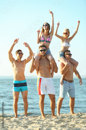 Guys carrying girls on the shoulders, at the beach, outdoors
