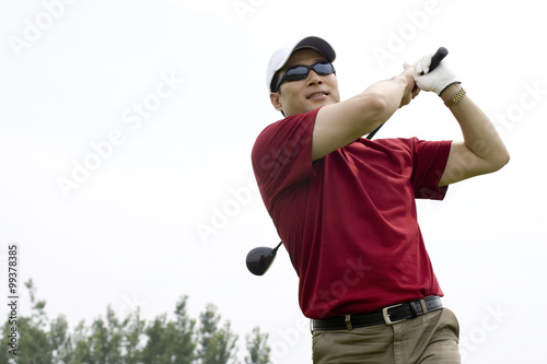 Male golfer swinging club