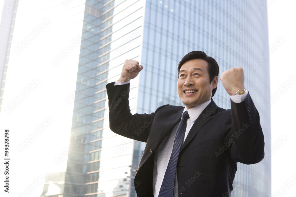 Businessman celebrating in front of office building Businessman celebrating in front of office building