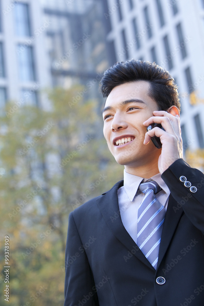 Businessman outside buildings on his mobile phone Businessman outside buildings on his mobile phone