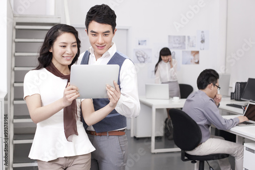 Cheerful office workers with digital tablet