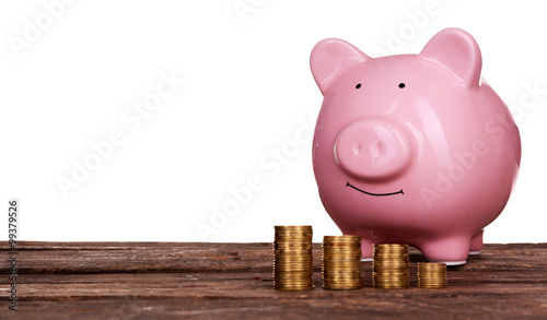 Piggy bank and coins on wooden table against white background