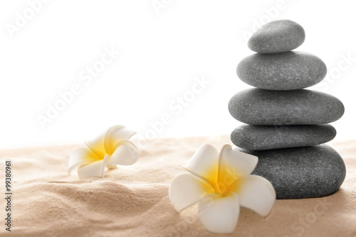 Few spa stones with plumeria on sand  isolated on white