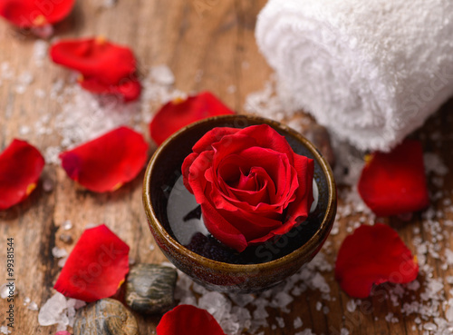 Towel and rose in bowl with petals ,salt on old wood 