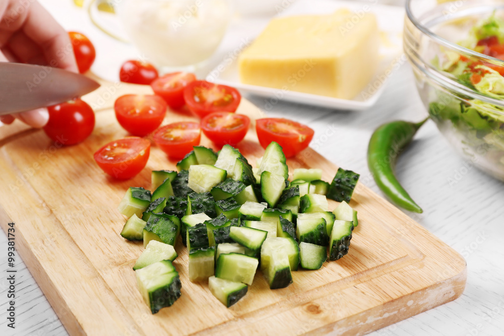 Female hands cutting vegetables for salad, at kitchen