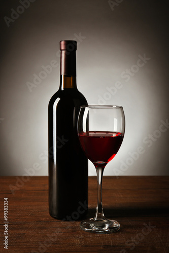 Wine in glass and in bottle on table on dark background