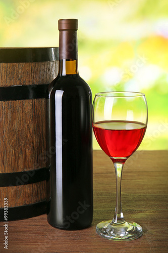 Red wine in glass and in bottle on blurred natural background