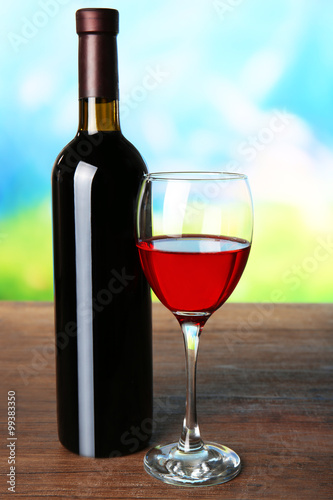 Wine in glass and in bottle on blurred natural background