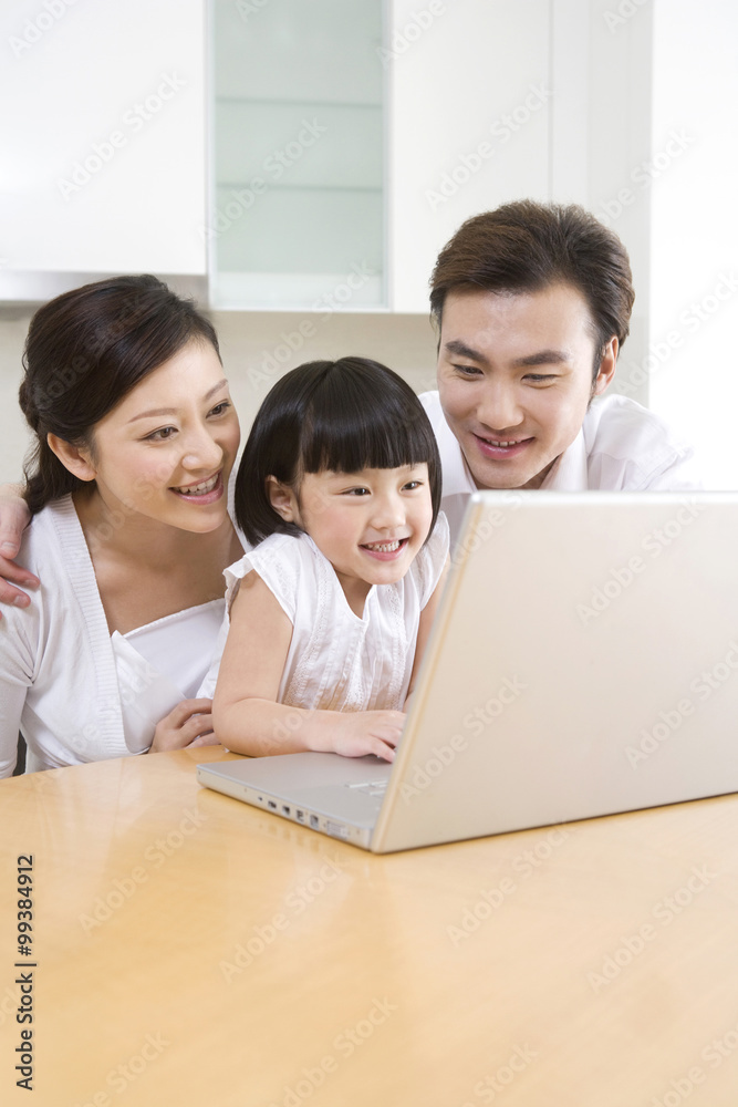 Little girl using laptop with her parents Little girl using laptop with her parents