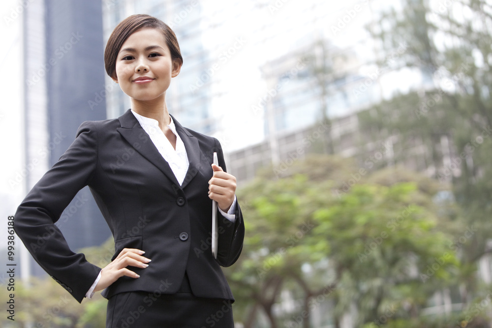 Confident businesswoman hand on hip with digital tablet in hand, Hong Kong Confident businesswoman hand on hip with digital tablet in hand, Hong Kong