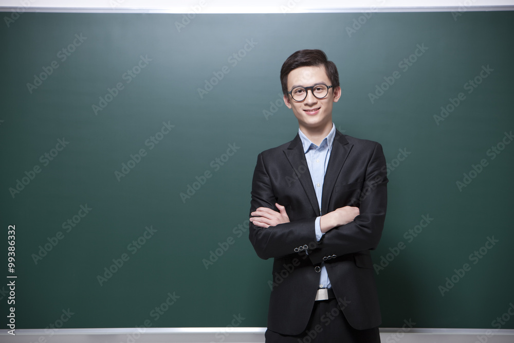 Professional male teacher arms crossed in classroom Professional male teacher arms crossed in classroom