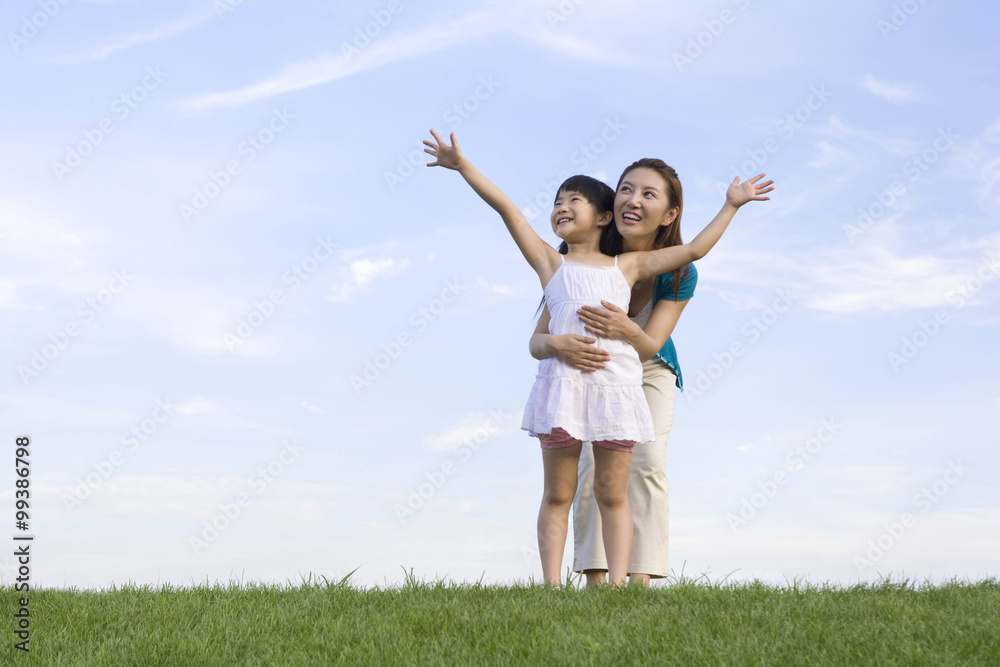 Mother and daughter standing on the grass