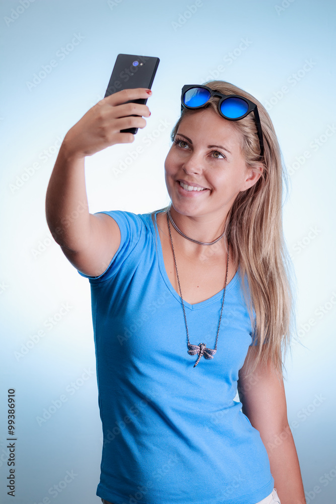 Woman taking self portrait with smartphone. Wearing blue shirt a